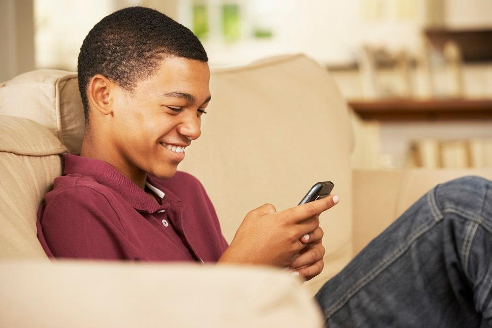 male teen sitting on couch looking at phone